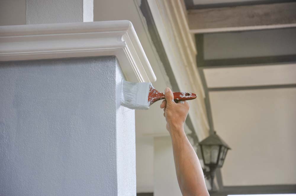 man hand painted a house pillar with brush